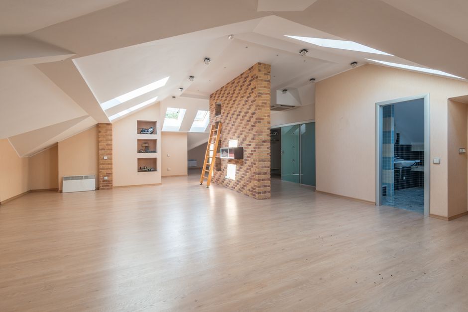 Empty loft room with skylights and exposed brick