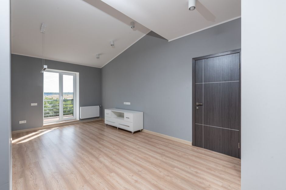 Empty new apartment room with wood floor and a balcony door