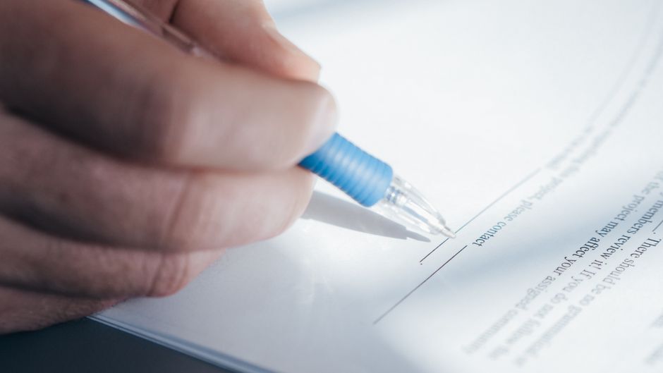 Hand signing a document with a pen