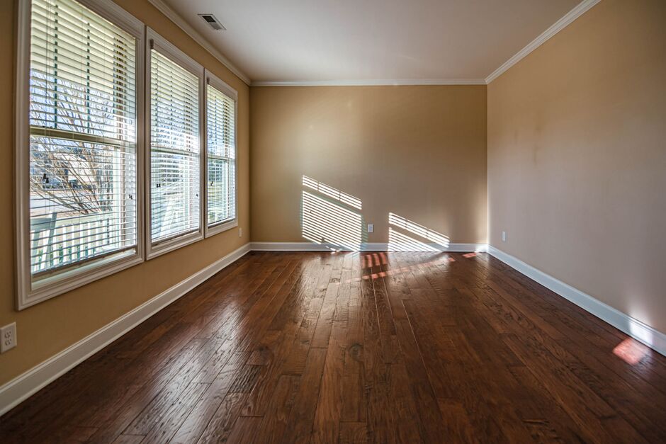 Sunlit empty room with wood floors and large windows