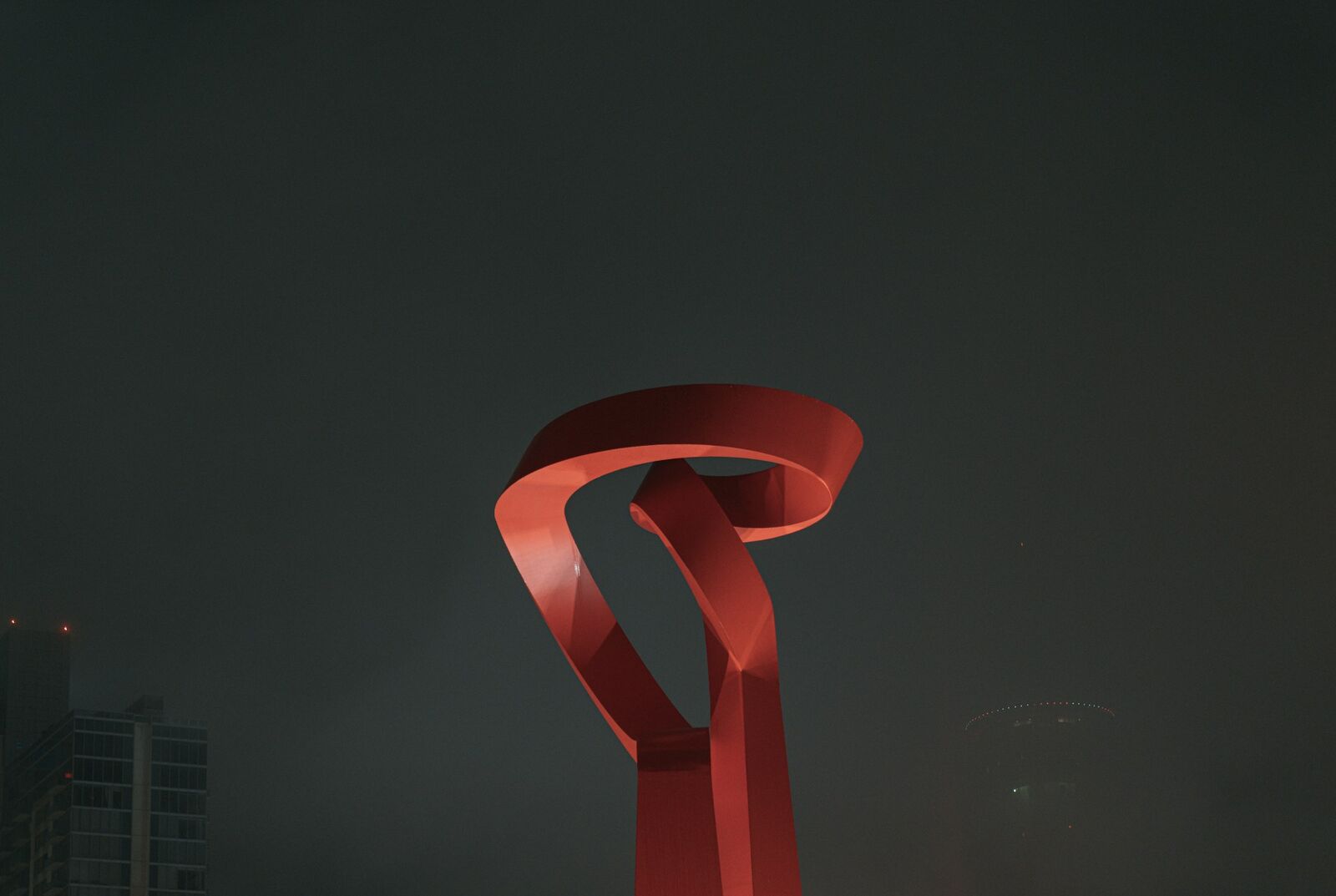 Red Torch of Friendship sculpture lit against the night sky in San Antonio